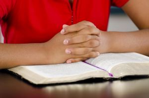 A person praying over the Bible.