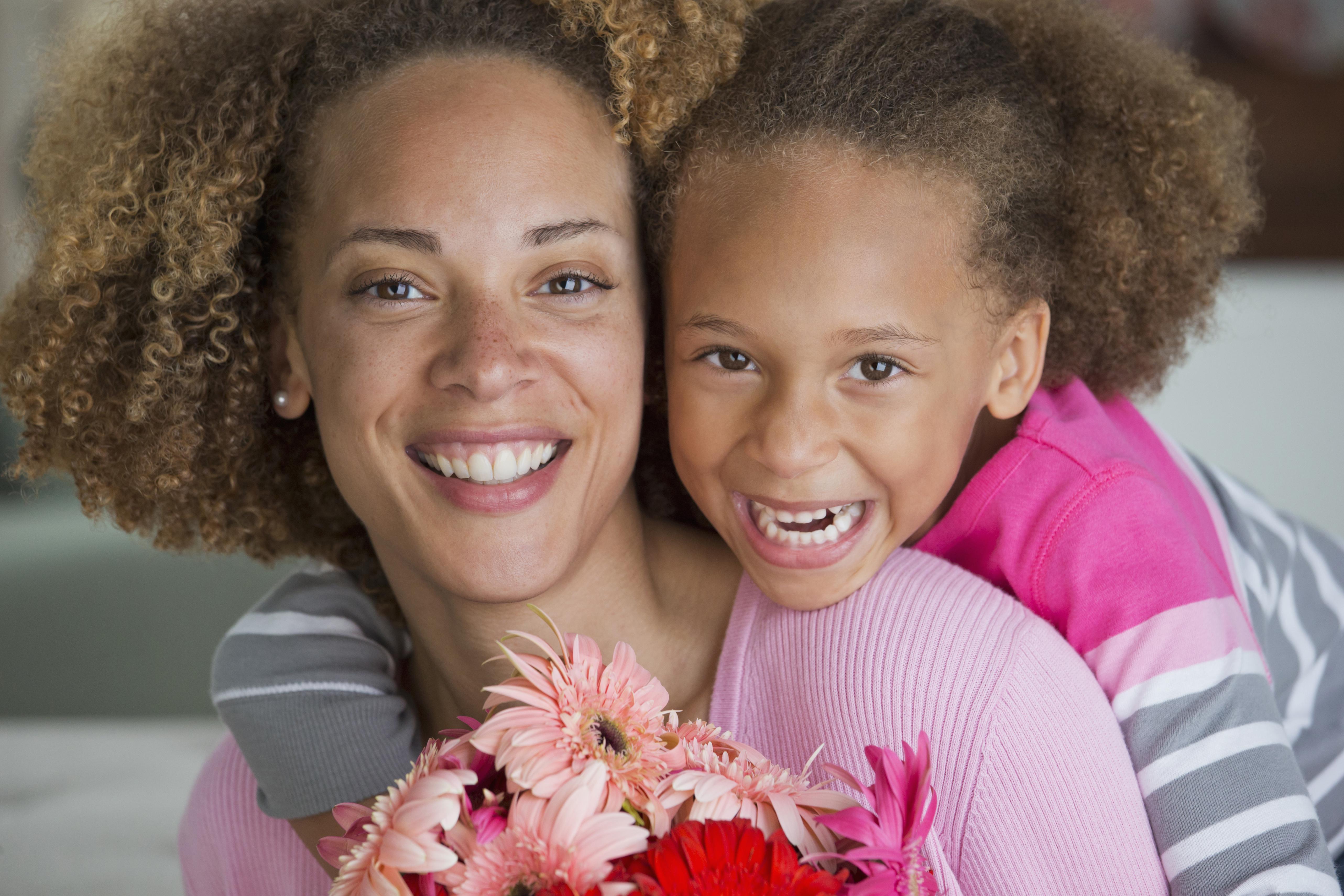 Black mother and daughter holding bouquet of flowers