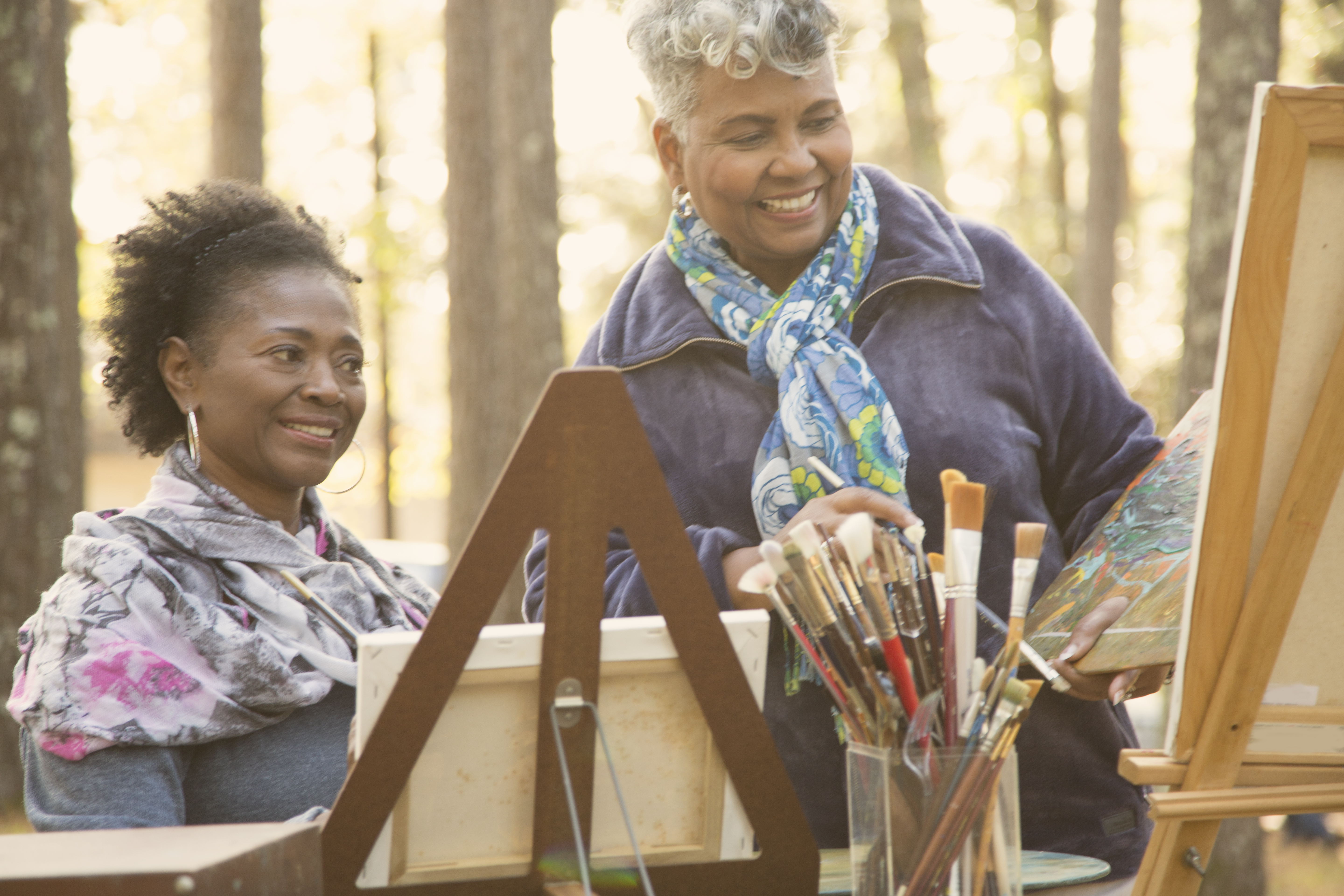Active senior adult friends enjoy art hobby outdoors.