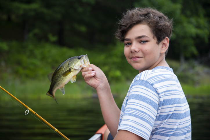 Happy young fisherman in a canoe with his catch