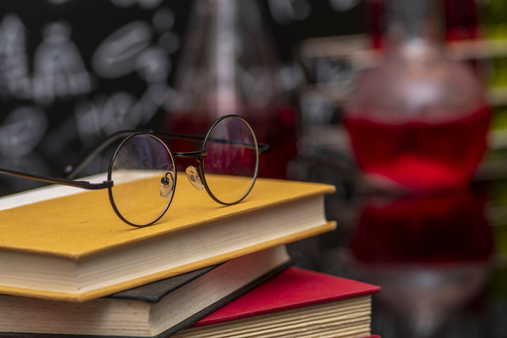 School supplies. Tubes with chemical liquids stand on a wooden table on a chalkboard background with digital formulas