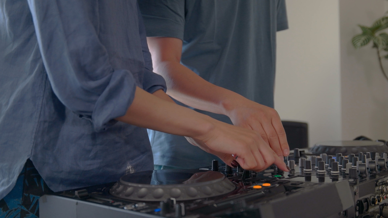 Young couple playing with DJ decks at home.