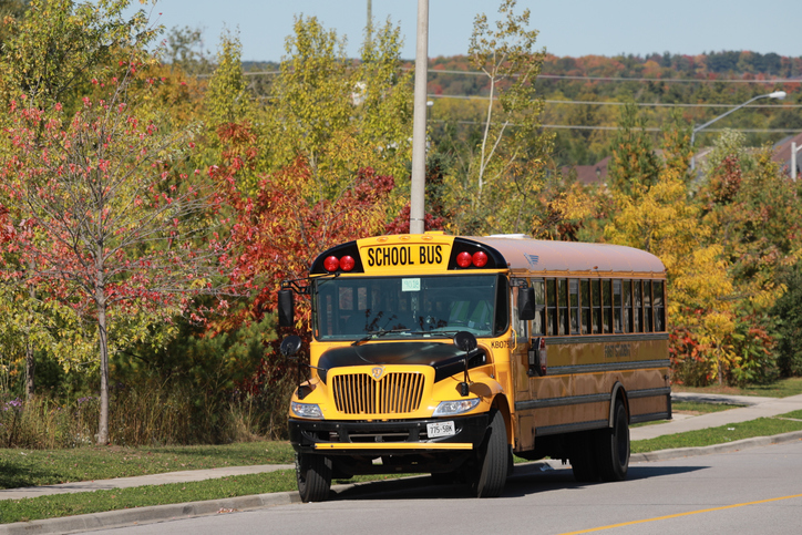 Yellow school bus on autumn background