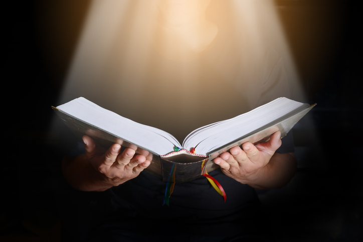 Midsection Of Woman Reading Bible In Room