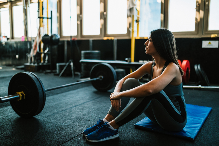 Woman resting after lifting weights in the gym