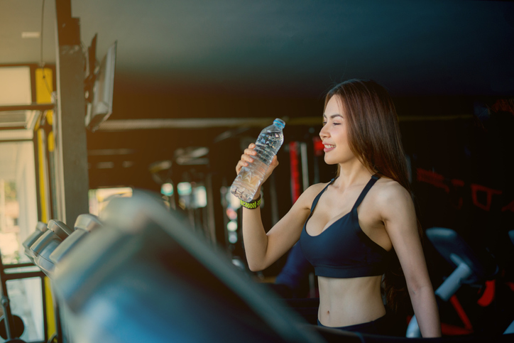 Young Woman Drinking Water From Bottle While Standing Outdoors